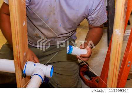 Plumber uses glue when joining plastic PVC pipes 115599564