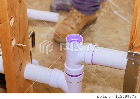 Technician plumber using glue is applied to plastic PVC pipes 115599575