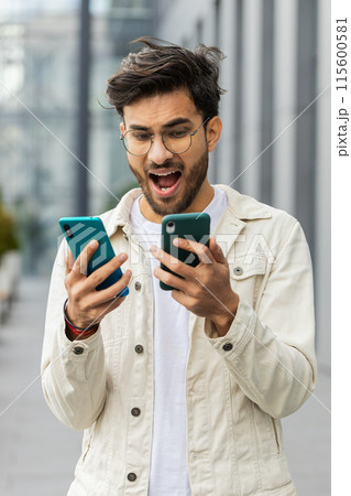 Irritated stressed business man talking on two mobile phones having conversation conflict quarrel Irritated stressed business man talking on two mobile phones having conversation conflict quarrel 115600581