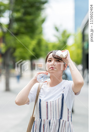 若くて可愛い日本人女性が屋外でタオルで汗を拭きながら水分補給|熱中症対策イメージ|水分補給イメージ 若くて可愛い日本人女性が屋外でタオルで汗を拭きながら水分補給|熱中症対策イメージ|水分補給イメージ 115602404