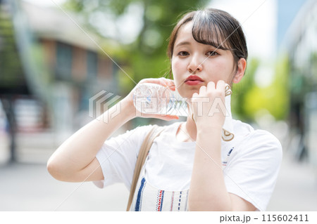 若くて可愛い日本人女性が屋外でタオルで汗を拭きながら水分補給｜熱中症対策イメージ｜水分補給イメージ 115602411
