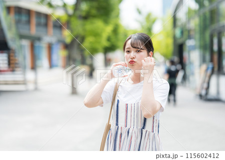 若くて可愛い日本人女性が屋外でタオルで汗を拭きながら水分補給｜熱中症対策イメージ｜水分補給イメージ 115602412