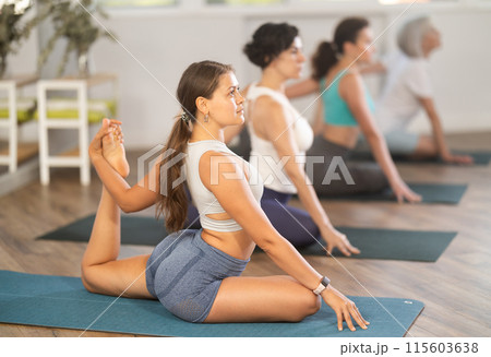 Young woman doing yoga in group in studio 115603638