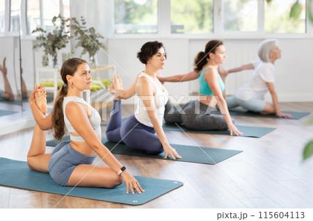 Girl performing one legged King Pigeon Pose at group yoga session Girl performing one legged King Pigeon Pose at group yoga session 115604113