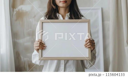 A woman is holding a white frame with a blank space inside 115604133