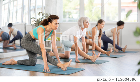 Woman performing Ardha Hanumanasana in group yoga class Woman performing Ardha Hanumanasana in group yoga class 115604396