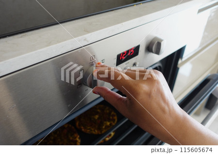Close up of men hand setting temperature control on oven. 115605674