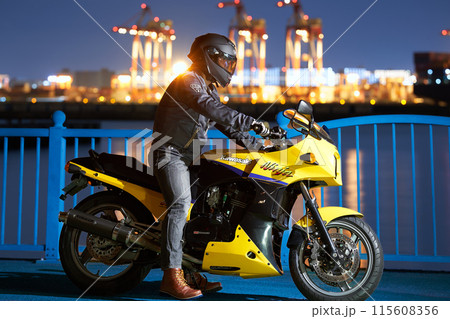 夜の港でバイクにまたがる男性 115608356