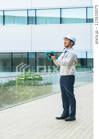 タブレットを使ってビルを点検するエンジニア 115610075