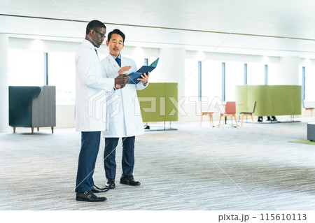 ロビーで会話する白衣を着た多国籍技術者 115610113