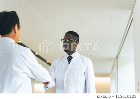 ロビーで握手する白衣の多国籍グループ ロビーで握手する白衣の多国籍グループ 115610129