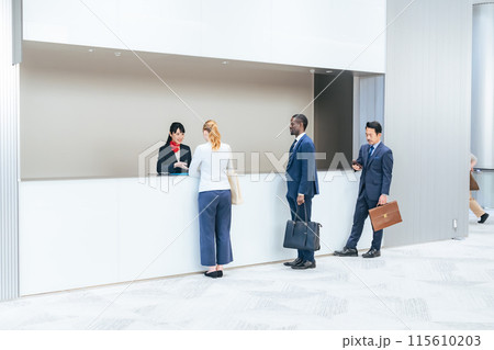 ホテルのフロントで手続きする多国籍の人々 115610203