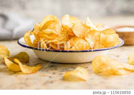 Crispy Potato Chips in bowl on kitchen table. 115610850