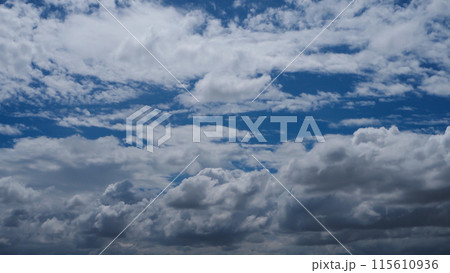 A blue sky with white clouds is adorned with a brilliant shade of blue, adorned with puffy, fluffy white clouds. 115610936