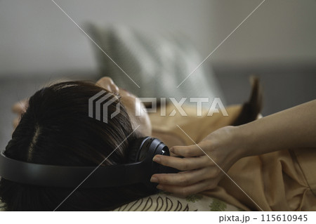 ソファに寝転んで音楽を聴く女性 ソファに寝転んで音楽を聴く女性 115610945