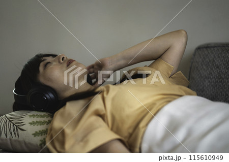 ソファに寝転んで音楽を聴く女性 ソファに寝転んで音楽を聴く女性 115610949
