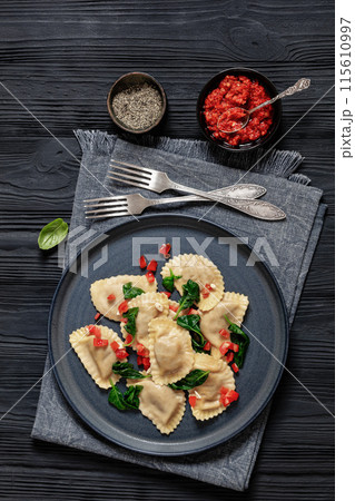 italian pasta mezzelune on a plate, top view 115610997