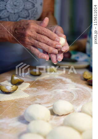 Preparation of homemade fruit dumplings with plums. Czech specialty of sweet good food. Dough on kitchen wooden table with hands. Preparation of homemade fruit dumplings with plums. Czech specialty of sweet good food. Dough on kitchen wooden table with hands. 115611014