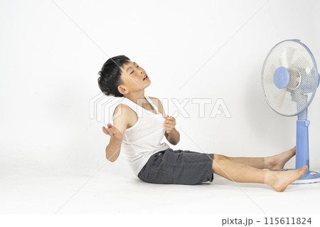 部屋で小学生の男の子がランニングシャツを着て、扇風機の前で暑くてぐったりしている様子 部屋で小学生の男の子がランニングシャツを着て、扇風機の前で暑くてぐったりしている様子 115611824