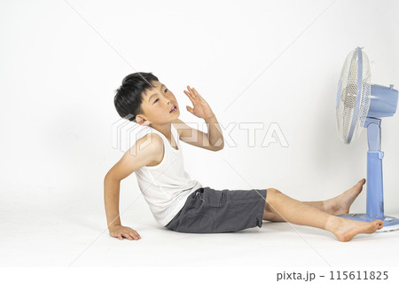 部屋で小学生の男の子がランニングシャツを着て、扇風機の前で暑くてぐったりしている様子 部屋で小学生の男の子がランニングシャツを着て、扇風機の前で暑くてぐったりしている様子 115611825