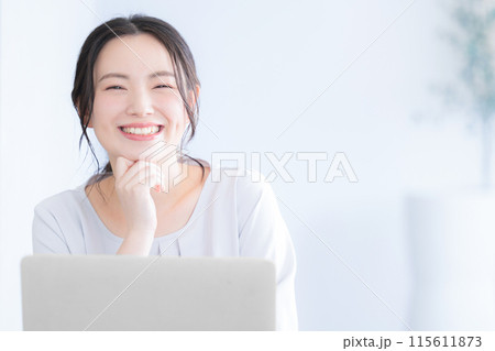 パソコンを操作する若い女性　カメラ目線の笑顔 115611873