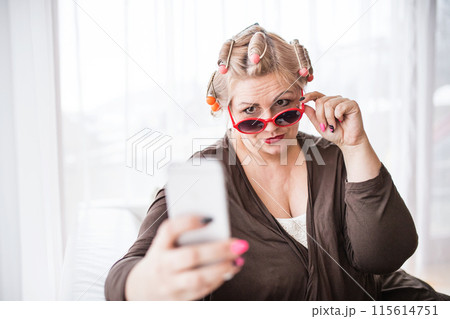 Portrait of beautiful young overweight looking at mirror, having fun. taking selfie with smartphone. Portrait of beautiful young overweight looking at mirror, having fun. taking selfie with smartphone. 115614751