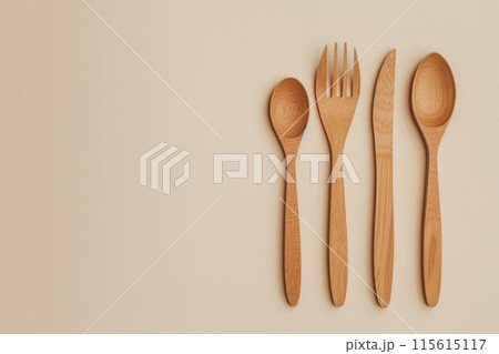 Top view of an elegant wooden spoon, fork, and knife arranged on a beige background 115615117