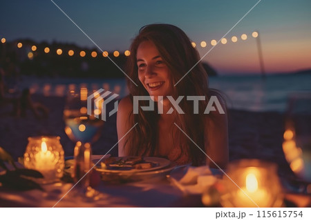 Smiling woman enjoys a serene beachside dinner as the sun sets, creating a warm ambiance 115615754