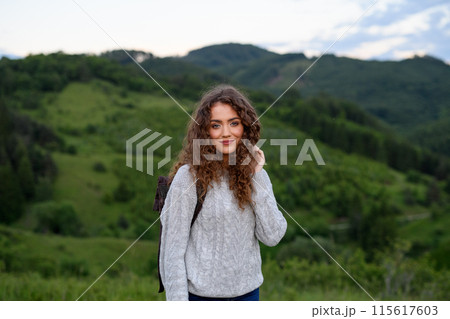 Young tourist woman traveller with backpack walking in nature. Active hiker on trail in mountains enjoying sunset. 115617603