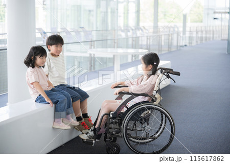 車椅子にのる小学生と目線を一緒に話す友達 115617862