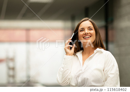 Business Communication Offer. Happy Young Businesswoman Talking On Mobile Phone, Communicating And Smiling Having Successful Conversation With Client Standing Indoors, Empty Space For Text 115618402