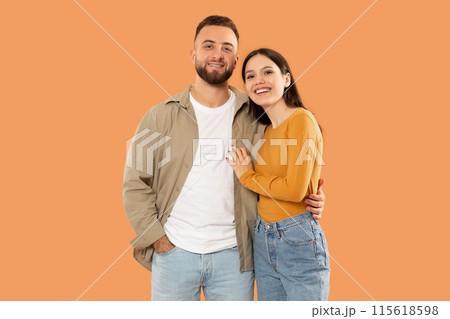 A man and a woman are standing side by side, facing forward. They appear to be looking in the same direction. Both individuals are casually dressed and have neutral expressions on their faces. 115618598