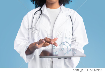 Young black woman doctor therapist in white coat uses tablet with blank screen and molecules, isolated on blue studio background, collage. App for medical, health care, science website Young black woman doctor therapist in white coat uses tablet with blank screen and molecules, isolated on blue studio background, collage. App for medical, health care, science website 115618953