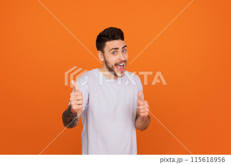 A cheerful european guy gives a thumbs up, symbolizing approval and positivity, showcasing friendship 115618956