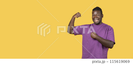 Strength And Victory. Joyful Black Guy Showing Biceps Muscles On Hand And Gesturing Yes In Joy, Standing Over Yellow Studio Background, Smiling To Camera. Panorama With Copy Space Strength And Victory. Joyful Black Guy Showing Biceps Muscles On Hand And Gesturing Yes In Joy, Standing Over Yellow Studio Background, Smiling To Camera. Panorama With Copy Space 115619069