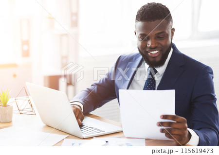 Satisfied african american businessman checking documents in modern office, side view, empty space 115619473