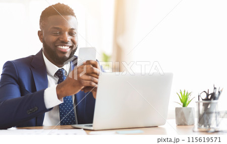 Happy african american businessman chatting on smartphone, sitting in modern office, copy space Happy african american businessman chatting on smartphone, sitting in modern office, copy space 115619571