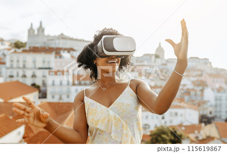 Cheerful surprised young african american lady in dress and vr glasses control copy space with hands, enjoy game and travel in city outdoor. Online app, gadget, virtual reality and entertainment Cheerful surprised young african american lady in dress and vr glasses control copy space with hands, enjoy game and travel in city outdoor. Online app, gadget, virtual reality and entertainment 115619867