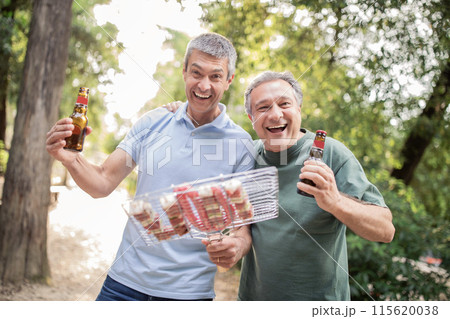 Portrait Of Two Cheerful Mature Friends Having Fun At Barbeque Party Outdoors, Happy Senior Men Holding Grill Basket And Drinking Beer, Cheerful Males Enjoying Summer Holiday And Outside Leisure 115620038