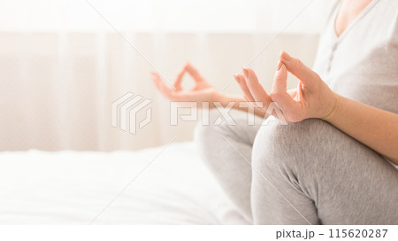 Age and healthcare. Hands of senior woman practicing yoga meditation, sitting in lotus position on bed, empty space Age and healthcare. Hands of senior woman practicing yoga meditation, sitting in lotus position on bed, empty space 115620287
