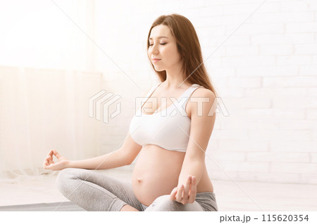 Pregnant woman doing yoga, practising padmasana in lotus position, copy space Pregnant woman doing yoga, practising padmasana in lotus position, copy space 115620354