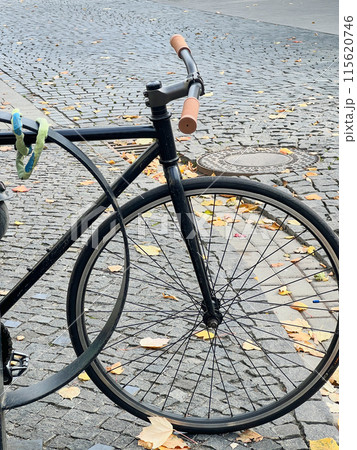 Cropped view of black fixed-gear bicycle, commonly known as a fixie on a cobblestone street. Cropped view of black fixed-gear bicycle, commonly known as a fixie on a cobblestone street. 115620746