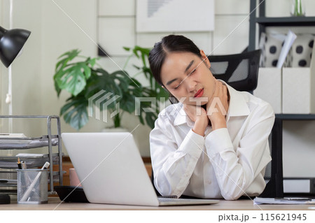 Businesswoman Experiencing Neck Pain at Work Desk in Modern Office Environment with Laptop and Office Supplies 115621945