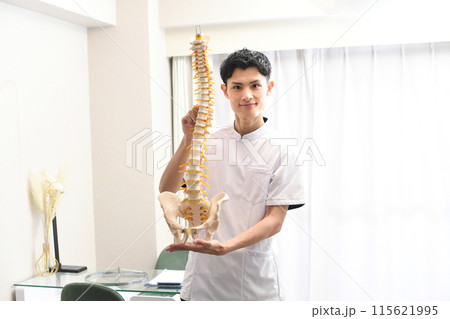 脊柱模型を持つ笑顔の白衣姿のアジア人男性 脊柱模型を持つ笑顔の白衣姿のアジア人男性 115621995