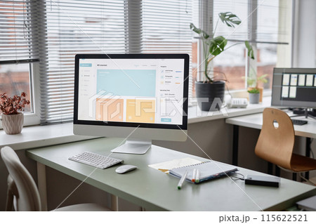 Background shot in pastel colors of office workplace table with computer monitor displaying page with online education courses. Room is cozy and full of light 115622521