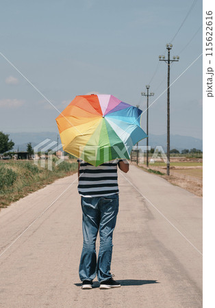 man carrying a rainbow umbrella on his shoulders man carrying a rainbow umbrella on his shoulders 115622616