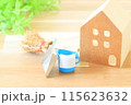 木の板の上にあるミニチュアの家とバケツとチリトリと箒 115623632