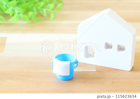 木の板の上にあるミニチュアの白い家とバケツ 115623634