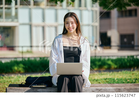 公園でパソコンをタイピングする若い女性 公園でパソコンをタイピングする若い女性 115623747
