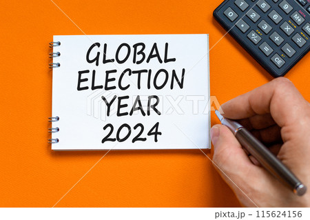 Global election year 2024 symbol. Concept words Global election year 2024 on beautiful white note. Beautiful orange background. Voter hand. Business Global election year 2024 concept. Copy space Global election year 2024 symbol. Concept words Global election year 2024 on beautiful white note. Beautiful orange background. Voter hand. Business Global election year 2024 concept. Copy space 115624156